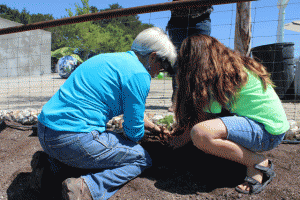 A volunteer from Glean SLO helps a student put in a pumpkin plant in the rainbow garden at Atypical Place in Paso Robles. Photo by Heather Young