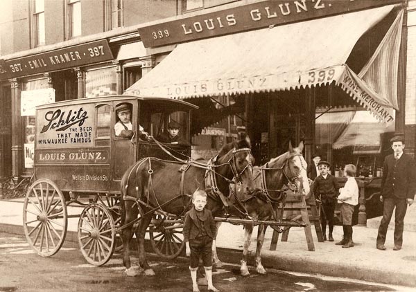Louis Glunz II, circa 1900, standing next to the horse in front of the family's wine store on Wells St. in Chicago.