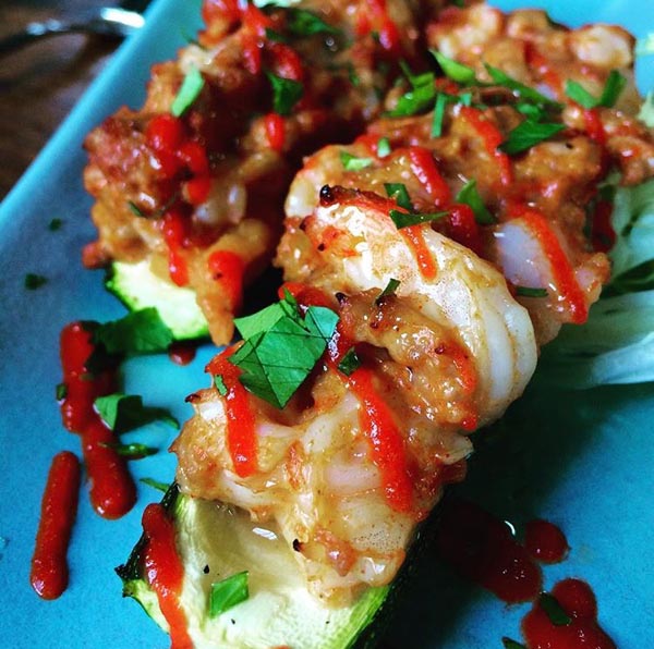 Ground pork and shrimp stuffed zucchini boats, topped with sriracha.
