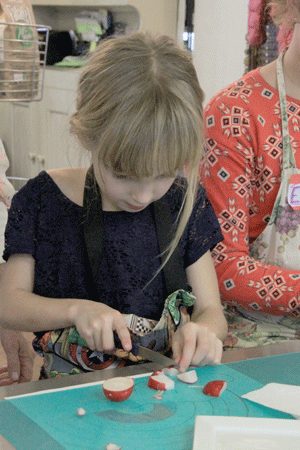 Atascadero resident Amalia Young, 6, cuts a radish during the children's cooking class on Friday. Photo by Heather Young