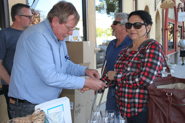 Atascadero Main Street Association member Larry Wysong puts a wristband on an attendee at the organization's quarterly event on Friday. Photo by Heather Young
