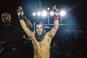 Chris Elisarraras raises his hands in victory following his MMA fight against Daniel Robles in June (photo by Dave Flores).