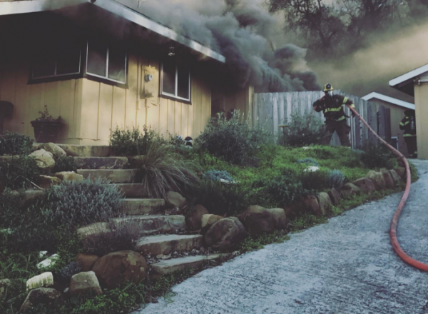 Firefighter pulling the initial fire attack line to the residence.