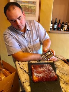 Ian Adamo dusting powdered sugar on his gluten-free apple cake