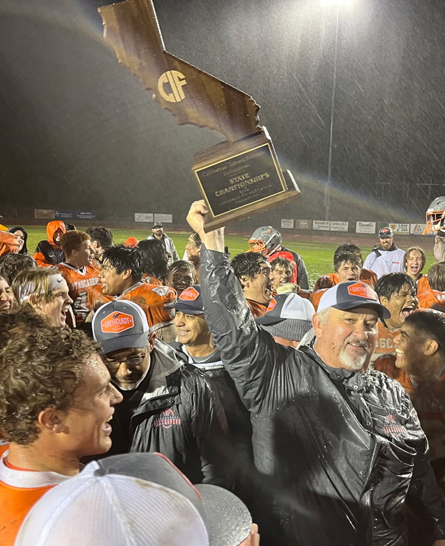 Coach Vic Cooper holds the team's new trophy aloft