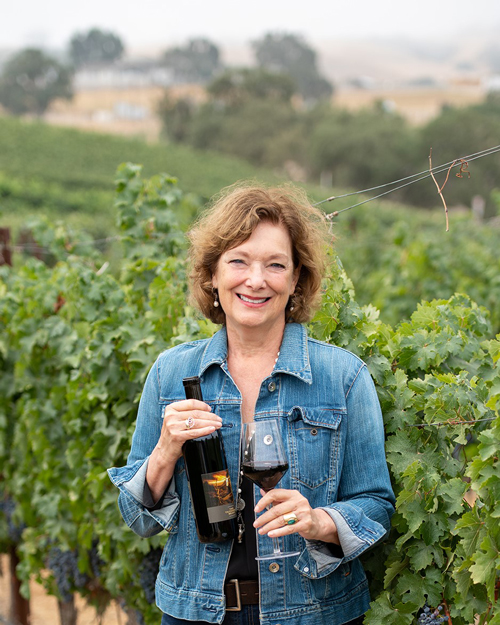 MWWine School's Melanie Webber in a Paso Robles vineyard holding wine made by one of her students.