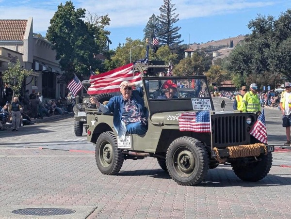 A man waves an American flag from a vintage military jeep during the 2026 Pioneer Day Parade in downtown Paso Robles.