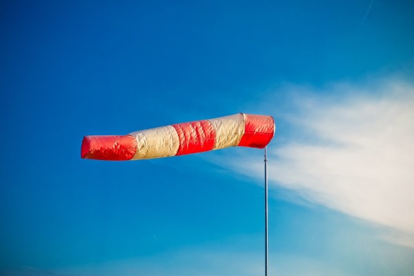 Wind sock blowing in high winds against a blue sky